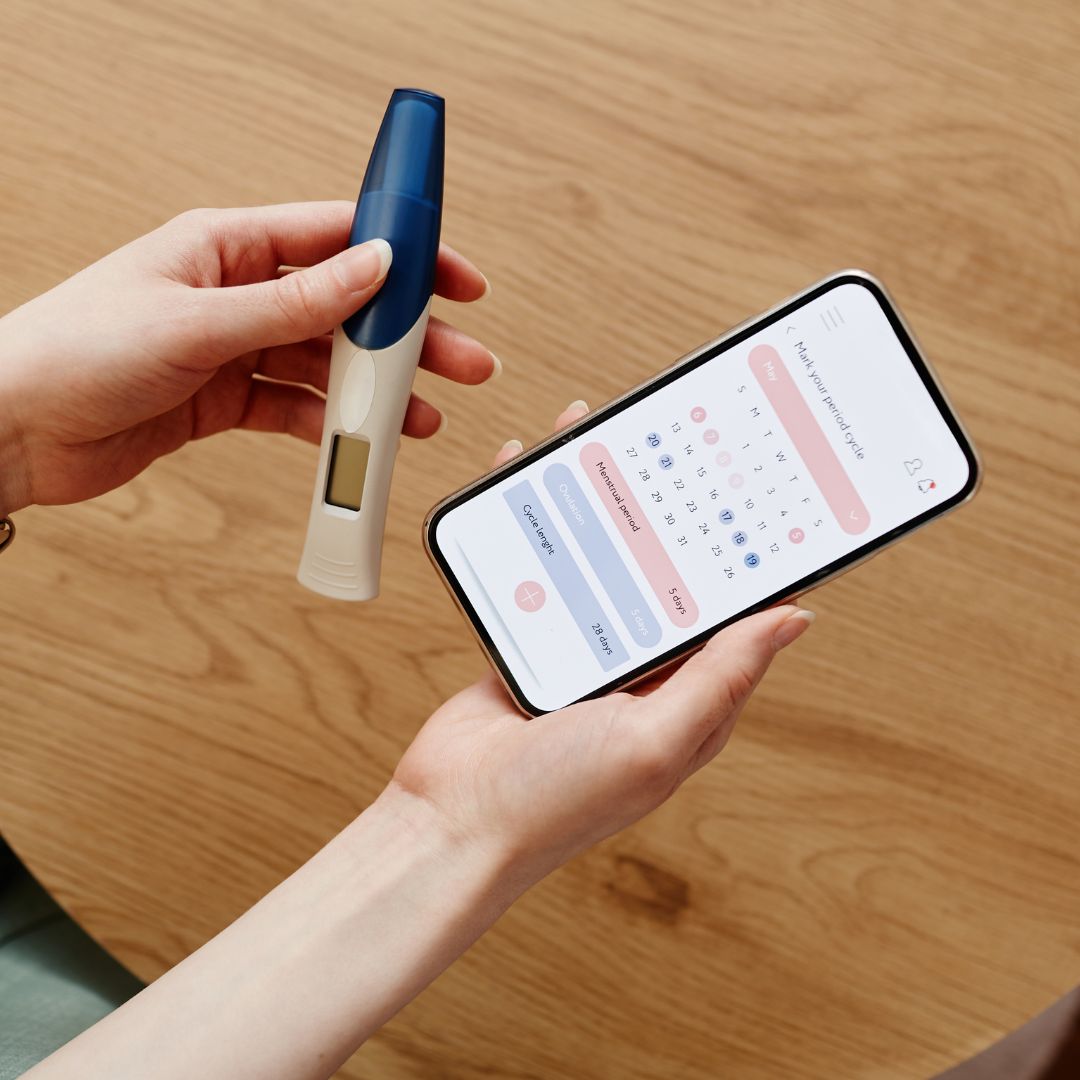 Person recording cervical mucus and basal body temperature data for PCOS cycle tracking.